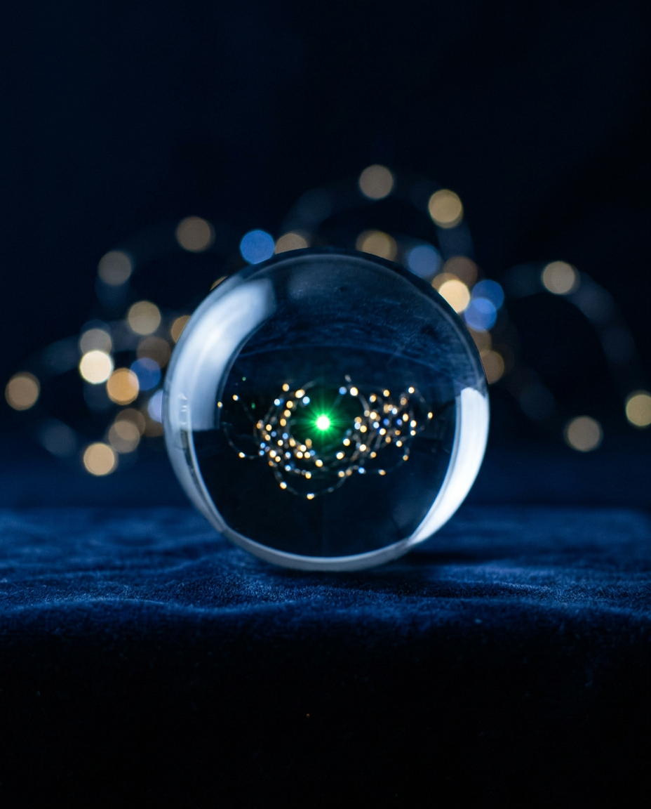A clear glass sphere bringing a scatter of blurred lights into sharp focus around one green point